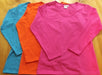 a flat  lay of long sleeve cotton t-shirts in hot pink, turquoise and jaffa